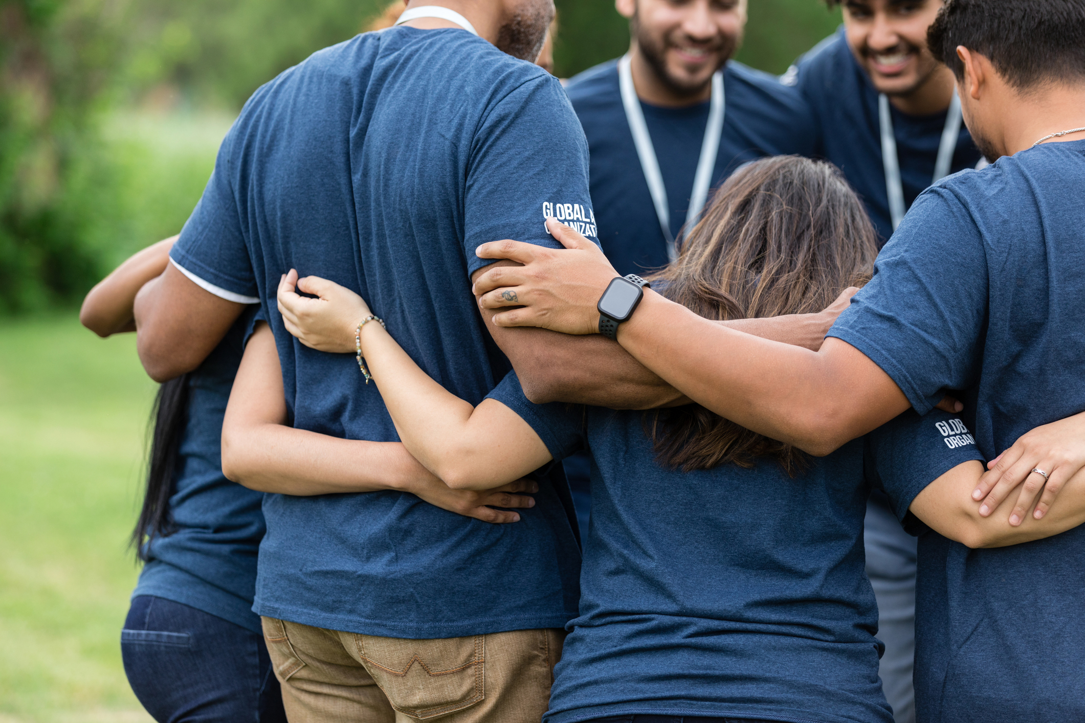 A team huddled together with arms around each other outdoors